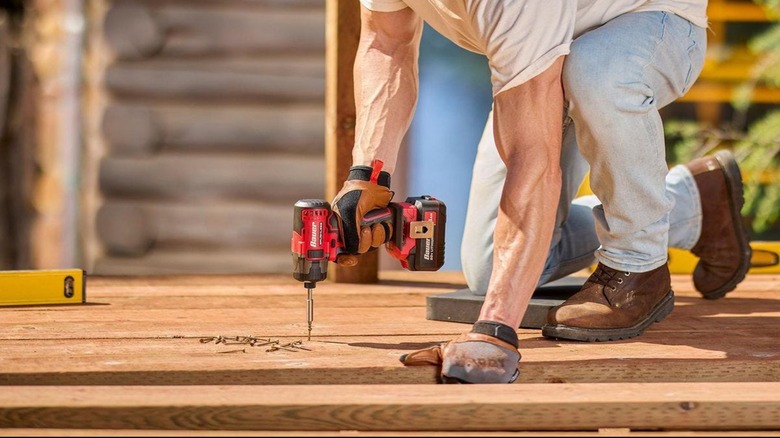 Man using an impact driver to build a deck.