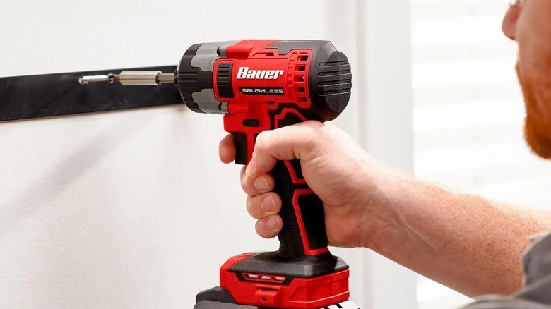 Man using an impact driver to fasten a bracket to the wall.