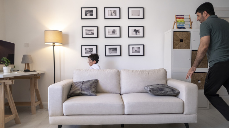 Framed photos arranged in a grid pattern on a wall behind a sofa