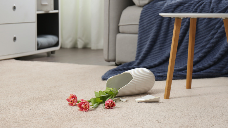 Broken vase on a carpet with flowers spilled out