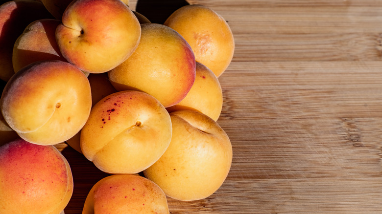 A close up of a pile of ripe Blenheim apricots on a wood surface
