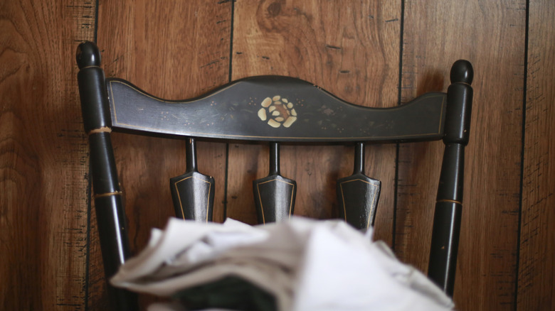 An antique black chair against dark wood paneling