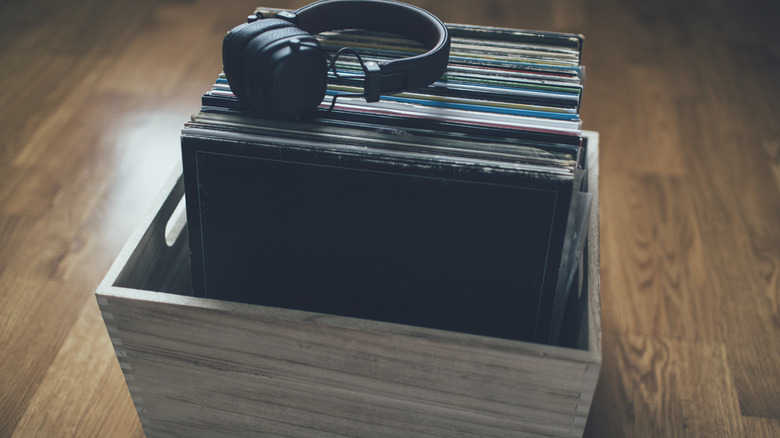 A storage box filled with vinyl albums with a pair of headphones on top.