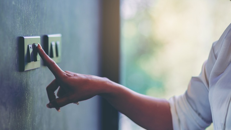 person pressing a light switch with one finger