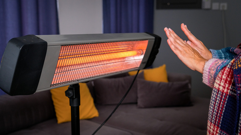 Person warming their hands in front of a portable space heater