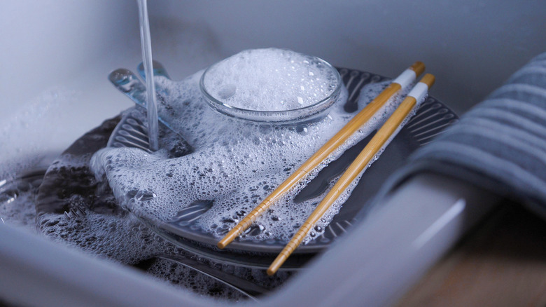 chopsticks in sink full of dishes