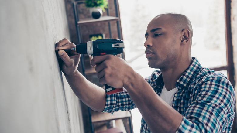 person drilling screw in wall