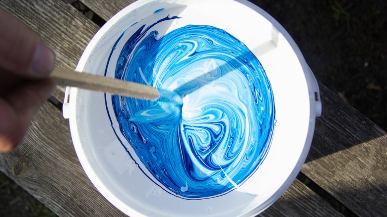 person stirring can of paint