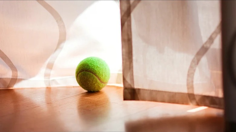 tennis ball on floor near curtain