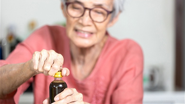 persona anziana che torce la bottiglia aperta