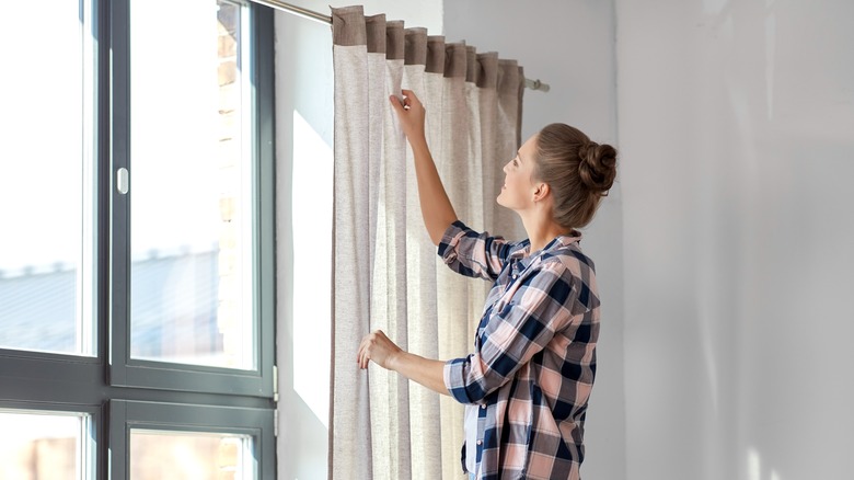woman hanging curtains