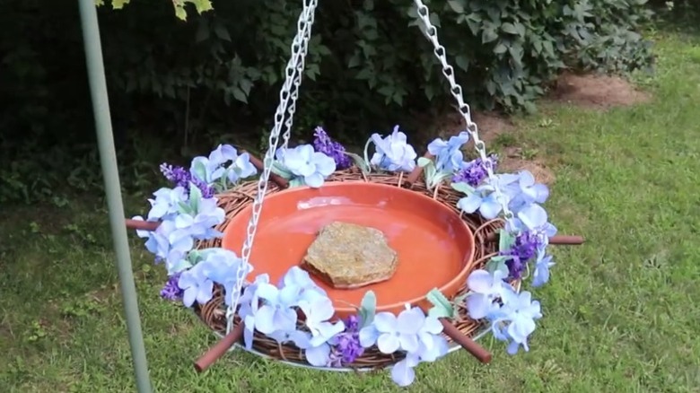 A floral bird bath hanging in a garden