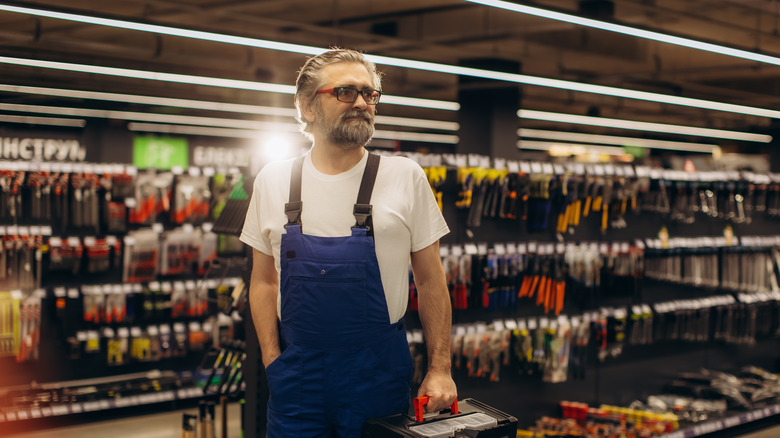 Man stands in hardware store aisle with various tools