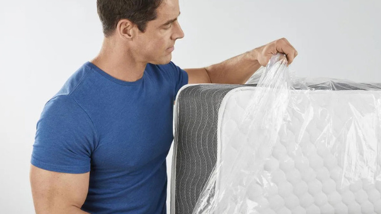 A man using Franklin's King-Size Mattress Bag to cover a mattress