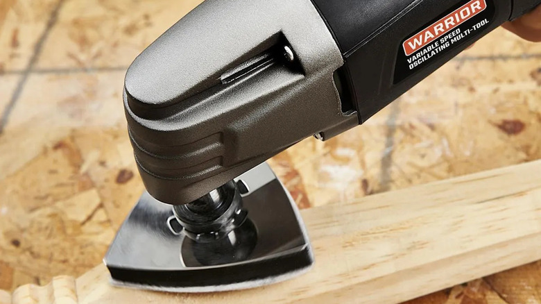 Harbor Freight's Warrior variable-speed oscillating multi-tool sanding a wood table leg