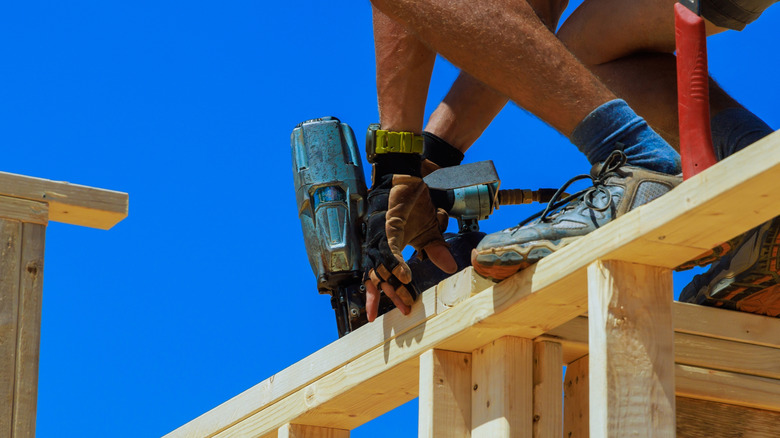 A man using a framing nailer on a construction site