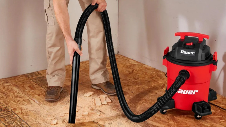 A person using Bauer's 6-Gallon, 4 Peak HP Wet/Dry Vacuum to clean up saw dust and other debris