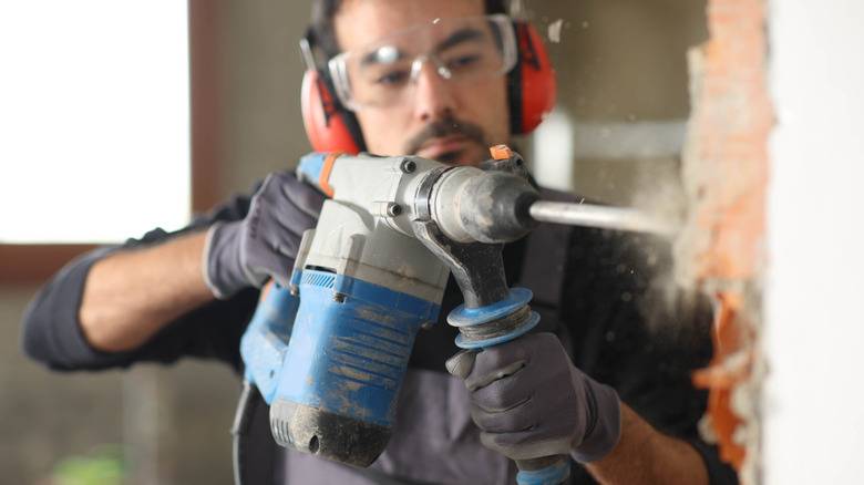 A worker demolishing a wall with a power tool