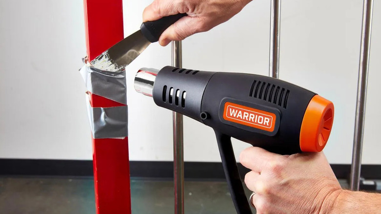 Close-up of a person using Warrior's 1500 Watt, 11 Amp, Duel Temperature Heat Gun