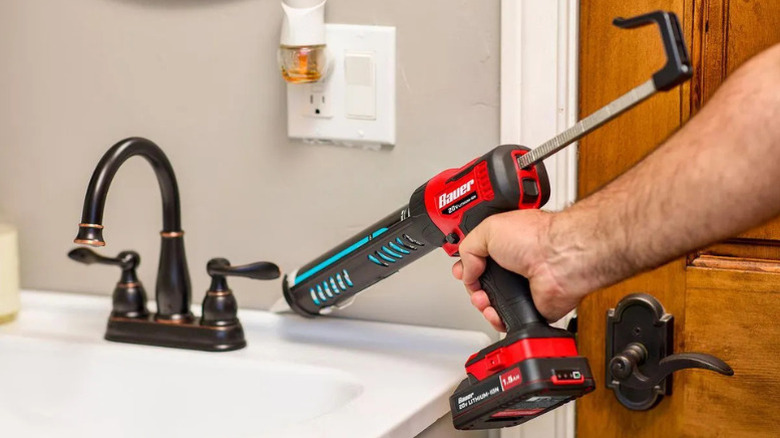 A person using Bauer's 20V Caulk and Adhesive Gun to caulk around a sink