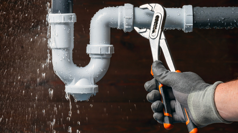 Close-up of a plumber fixing a leaky pipe with a wrench