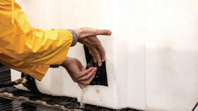 A person applying T-REX's Waterproof Tape to a severe leak