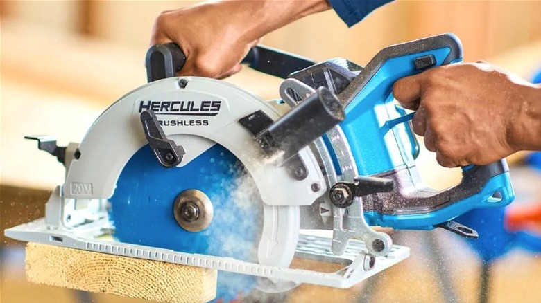 Person cutting wood board with Hercules 20V rear-handle circular saw from Harbor Freight.