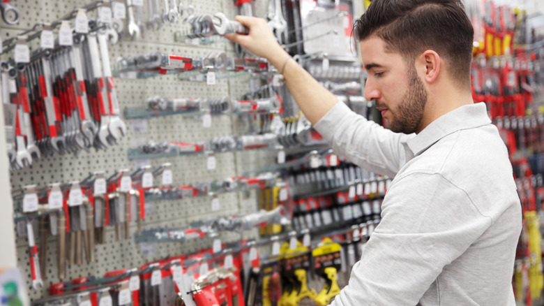 A man in a hardware store shopping for tools.