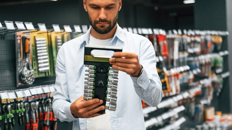 A man in a hardware store shopping for a socket set