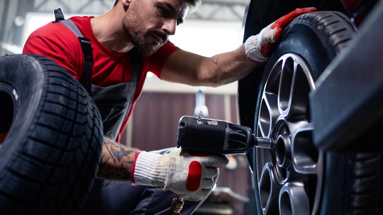 A man using an air impact wrench on lug nuts
