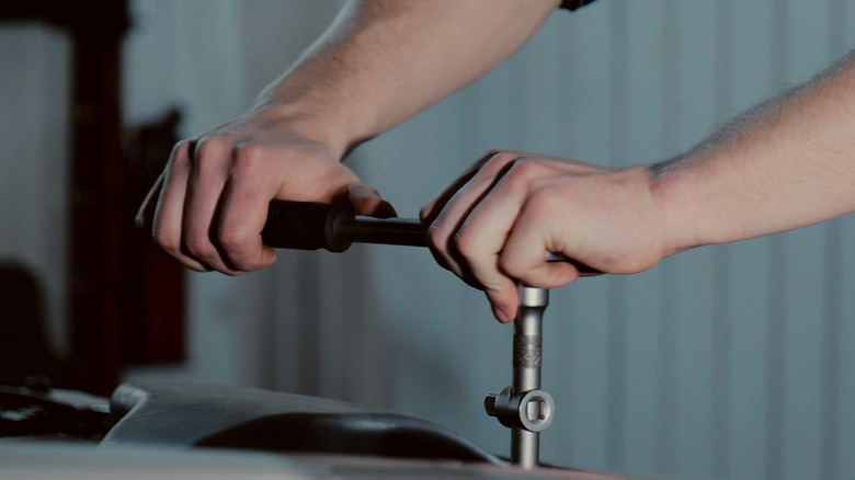 A man using a ratchet on a vehicle