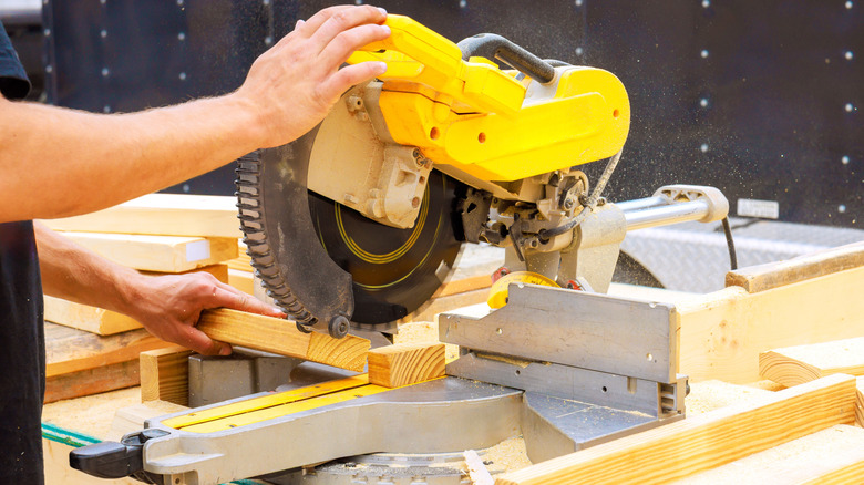 Person using a yellow miter saw to cut wood