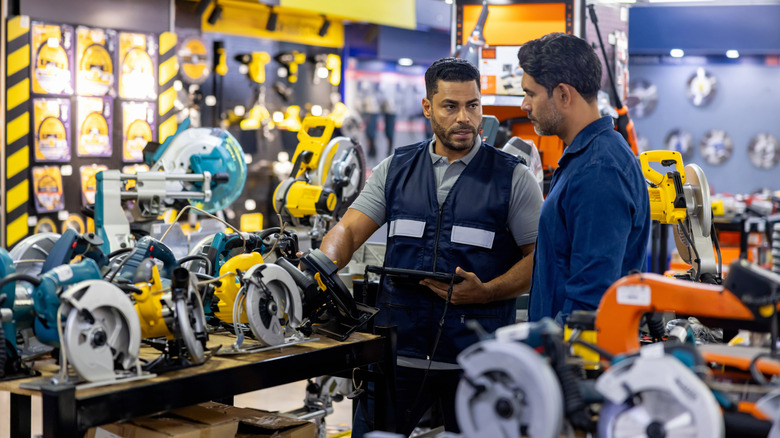 Two men discussing power tools in a hardware store