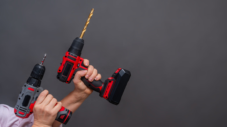 A person holding two cordless drills