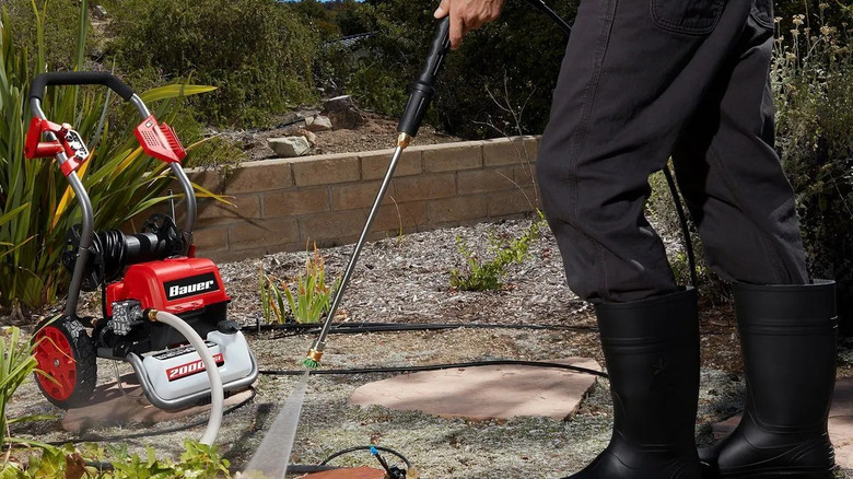 Close-up of a person using a Bauer pressure washer in a garden