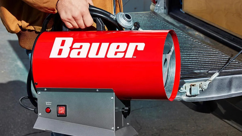 Close-up of a man holding Bauer's forced air propane portable heater