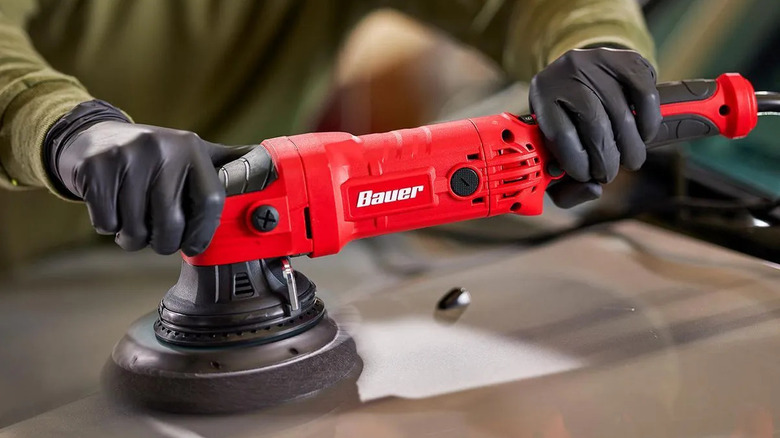 Close-up of a man using Bauer's long-throw random orbit DA polisher