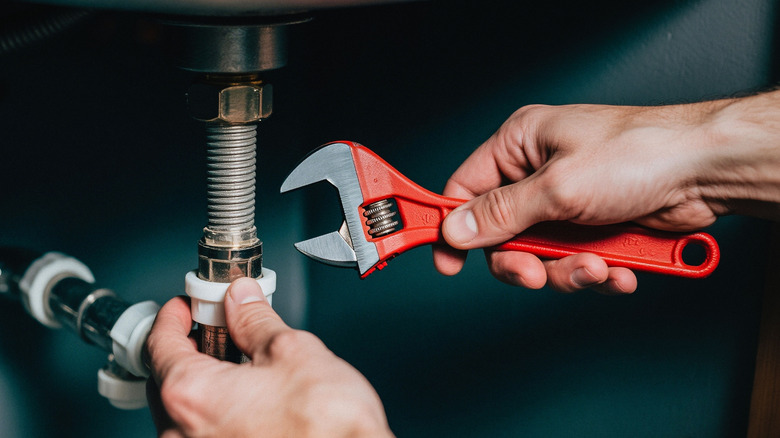 A man using a wrench to fix a sink