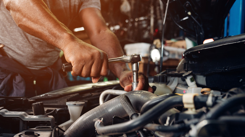 A man using a socket wrench on an engine