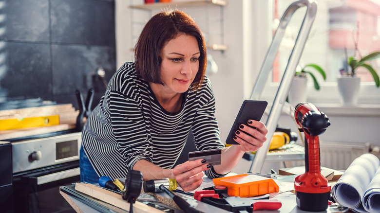 Woman shopping on her smartphone during home improvement project.