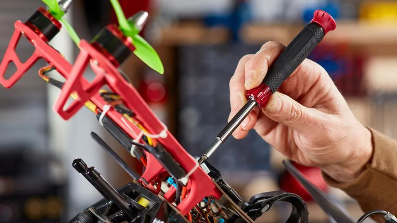 A person using the 14-in-1 Doyle screwdriver with a red and black handle.