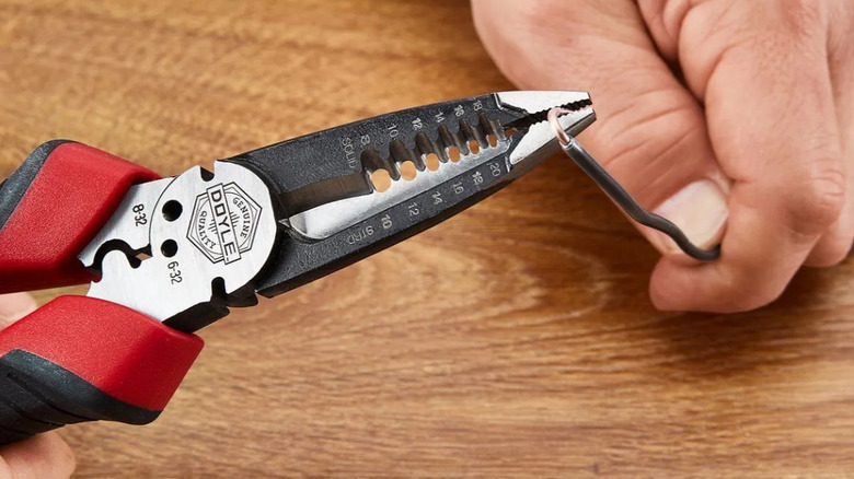 A person using the DOYLE pliers to trim an electrical wire.