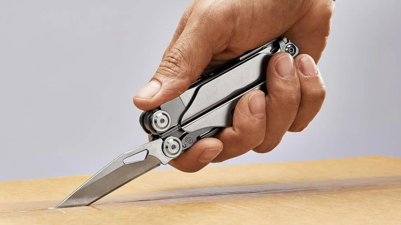 A person using the multi-tool to cut open a taped box.