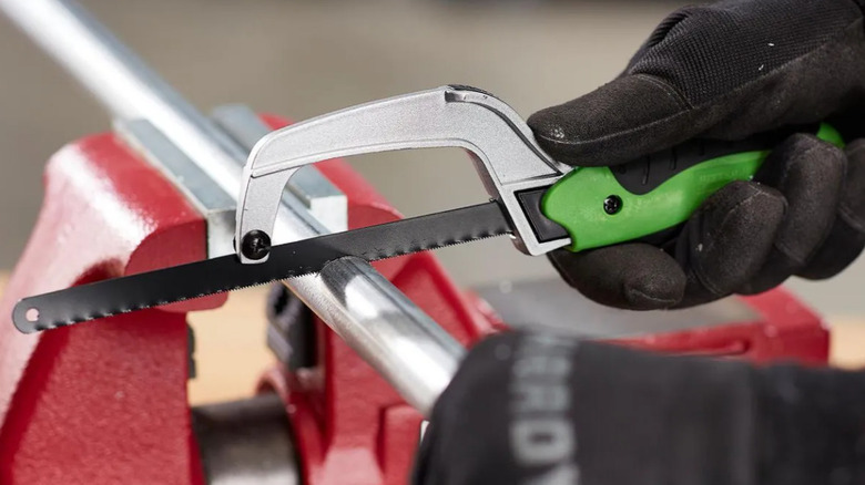 A person sawing a metal bar with the Pittsburgh multi-use saw.