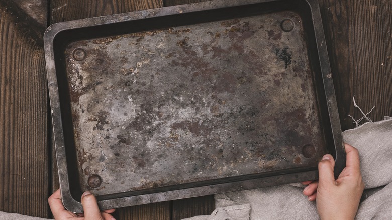 Woman holds a dirty baking tray
