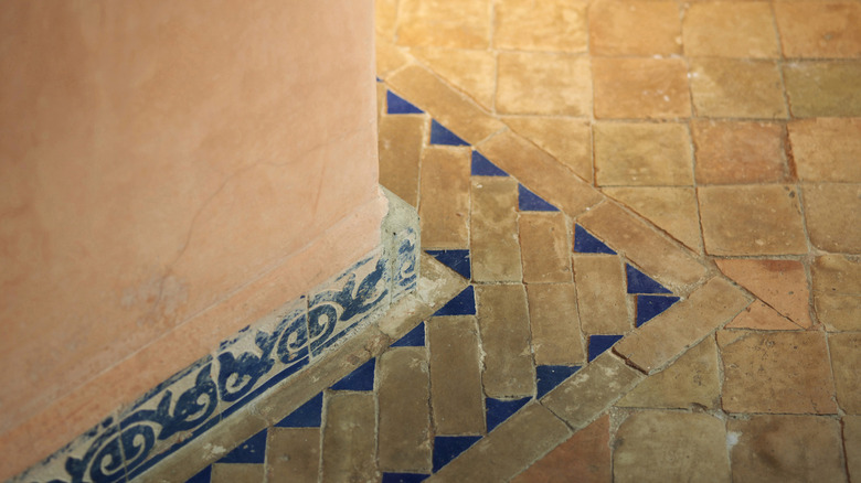 A Mediterranean terracotta tile floor with a blue insets next to a tile-edged wall