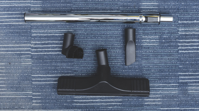 Vacuum cleaner attachments arranged on a carpeted floor.
