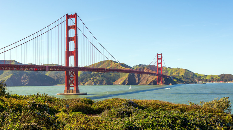 Golden Gate Bridge in San Francisco, CA as a sailboat passes underneath it