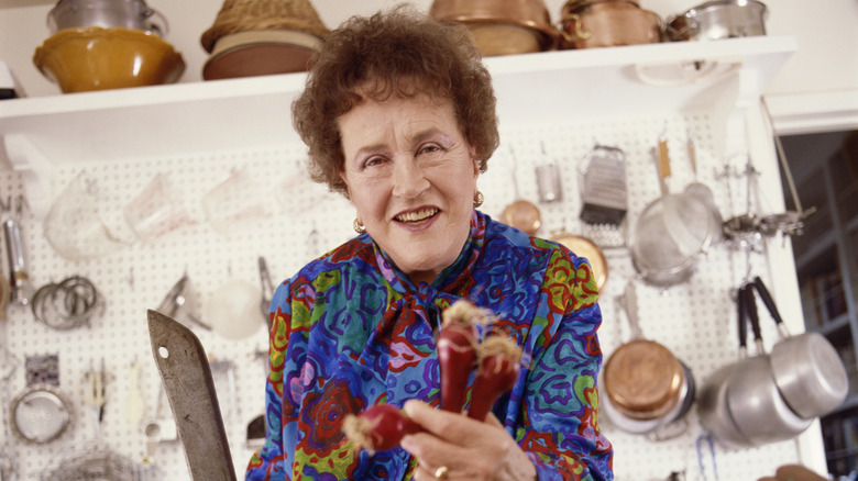 Julia Child in her kitchen holding red onions.