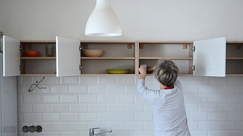 Person organizing kitchen cabinet